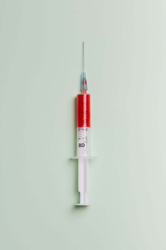 services-03 High-quality close-up of a syringe filled with red liquid on a light background.